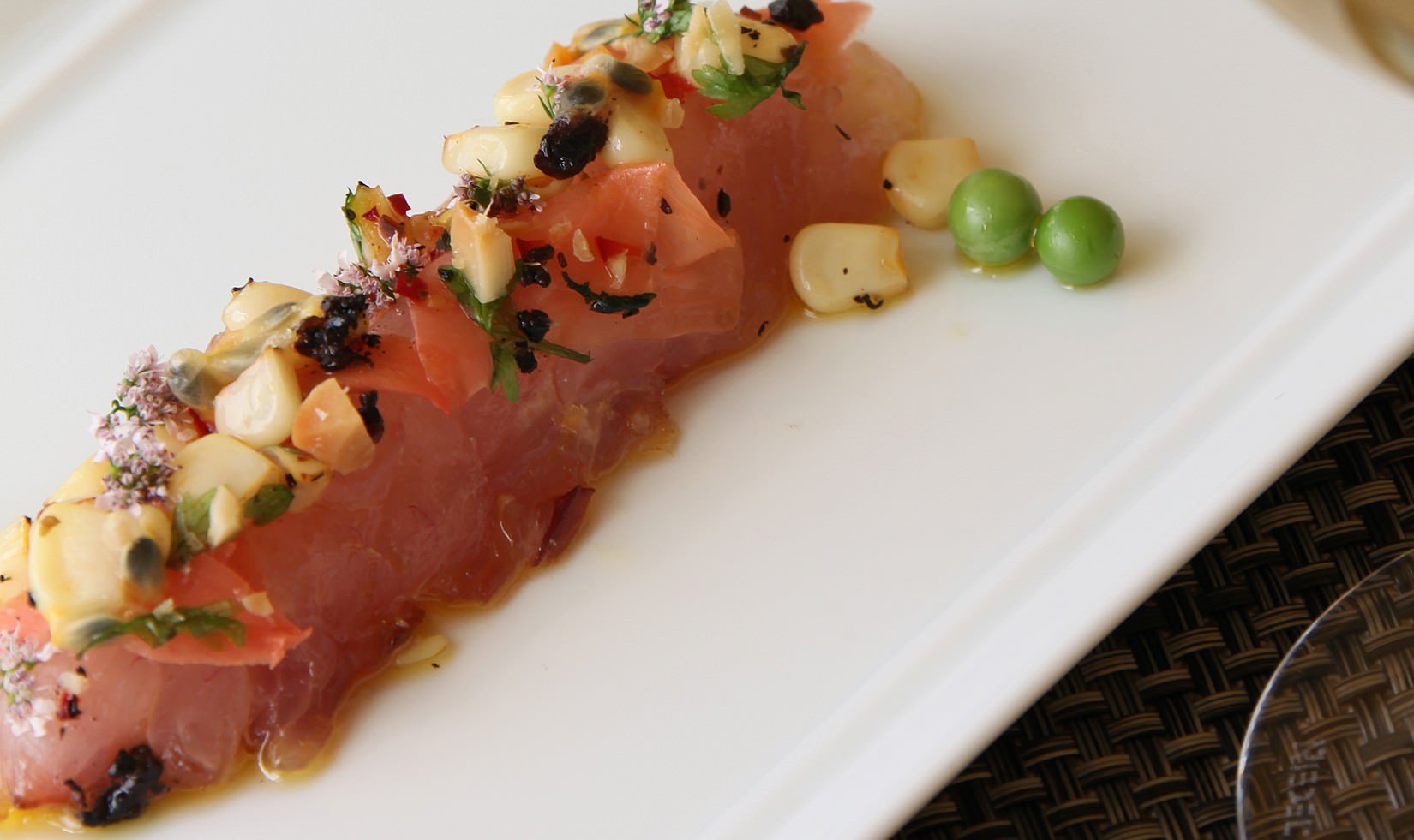 close up of Jordan Winery Hawaiian Tiradito with English peas and white corn