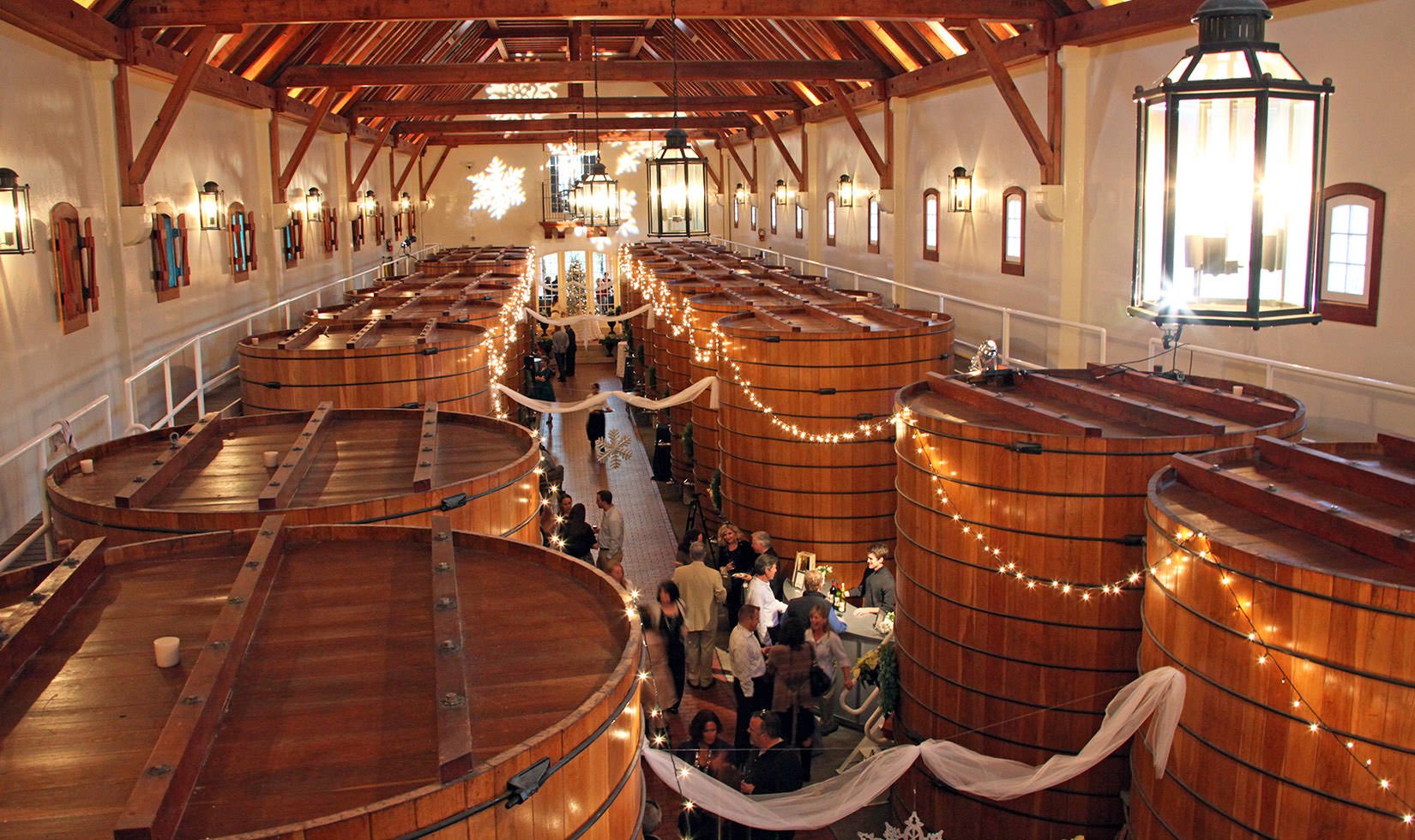 Guests gathered at a Christmas at Jordan event in the large oak tank room at Jordan Winery