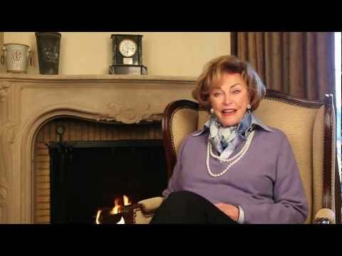 still shot of Ms. Sally Jordan seated in a chair in front of a fireplace in a video made by Jordan Winery