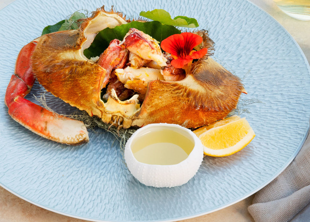 Dungeness crab boil with chardonnay butter on blue plate
