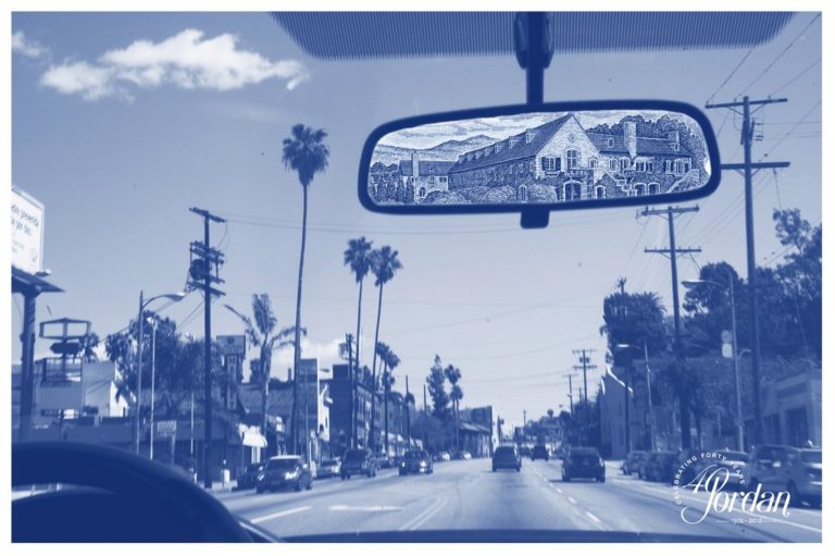 A piece of art from the 4 on 4 Jordan Winery art competition in Los Angeles. It's a blue monochromatic picture from the perspective of driving down a city street with palm trees. In the rear view mirror is Jordan Winery.