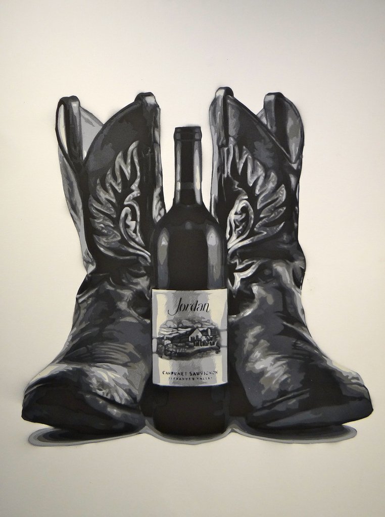 A piece of art from the 4 on 4 Jordan Winery art competition. It's black and white and features a bottle of Jordan's Cabernet Sauvignon between a pair of cowboy boots.