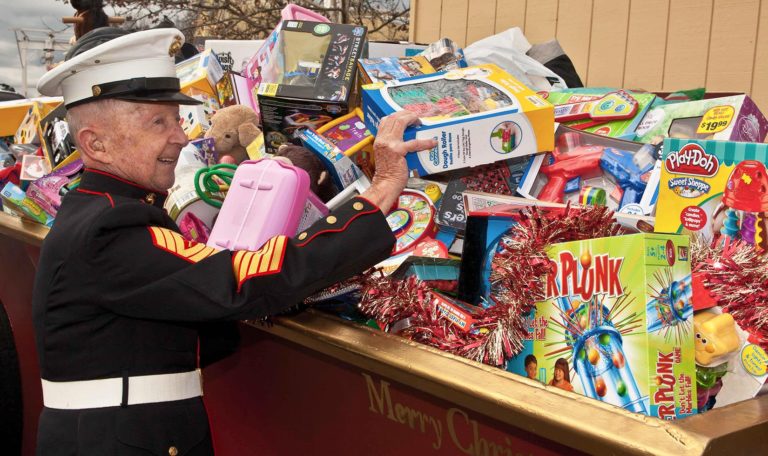 A member of the US Marine Corp grabbing a toy on top of a pile of toys in a sleigh
