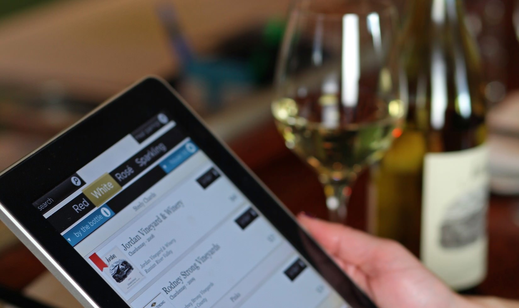 close up of an iPad displaying the Tastevin application with a bottle of Jordan Winery Chardonnay in the background