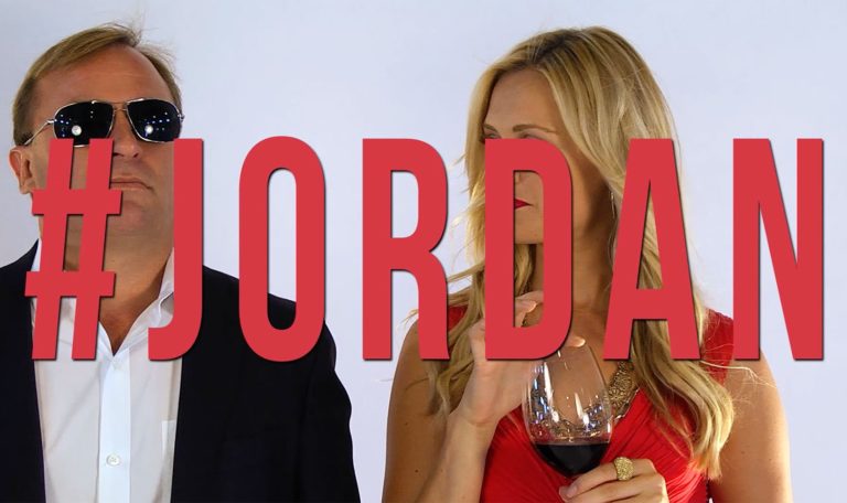John Jordan, CEO and proprietor of Jordan Winery standing with a woman sipping on glasses of Jordan Winery Cabernet with image text "#Jordan"