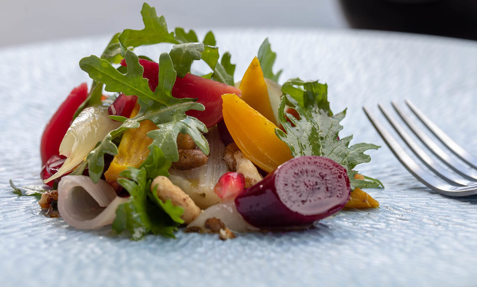 Roasted beet salad with black walnuts and greens on a white plate