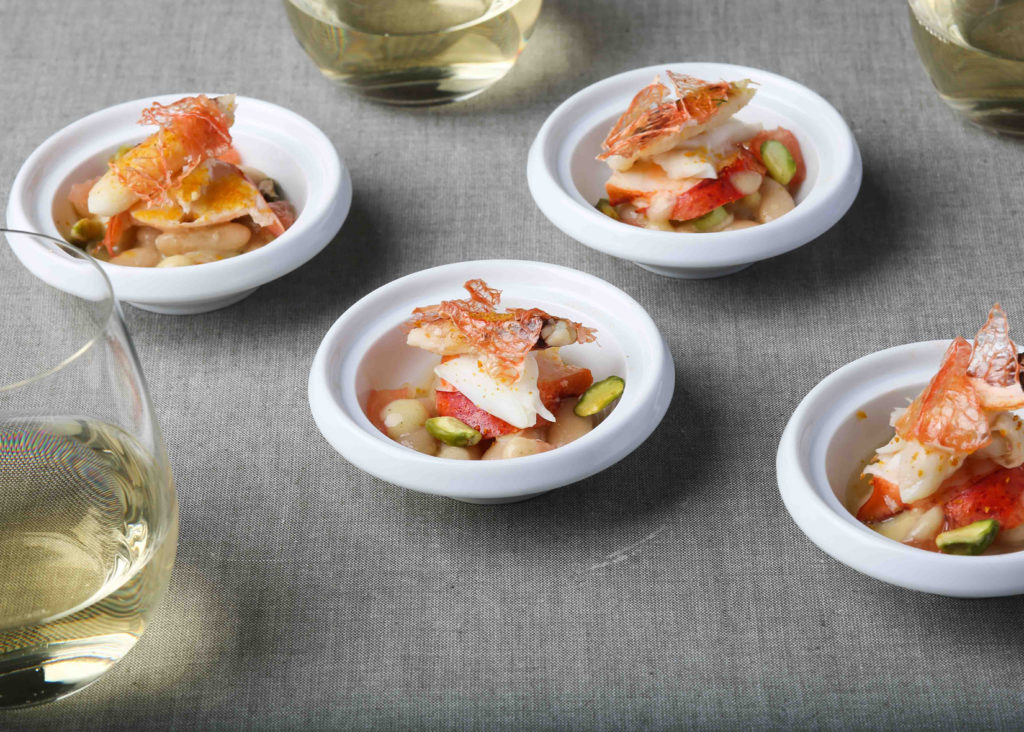 Crab with cannellini bean salad and citrus on multiple plates with wine pairing
