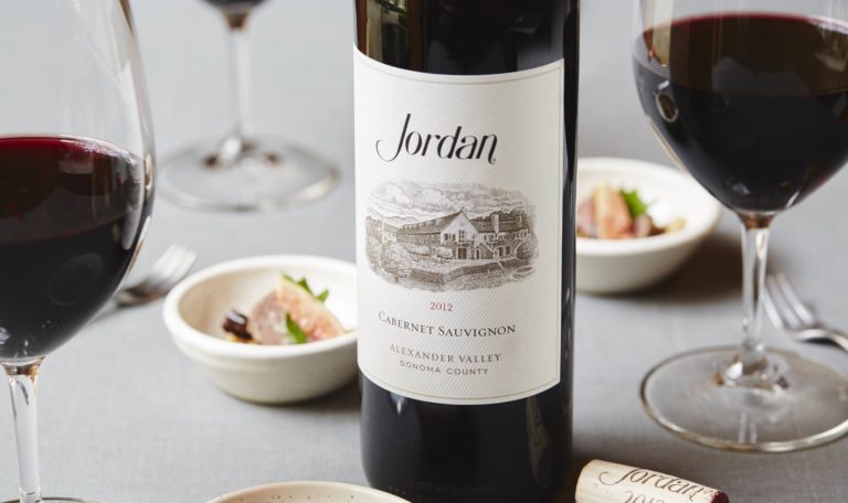 2012 Jordan Cabernet Sauvignon bottle with wine poured into glasses and food pairings.