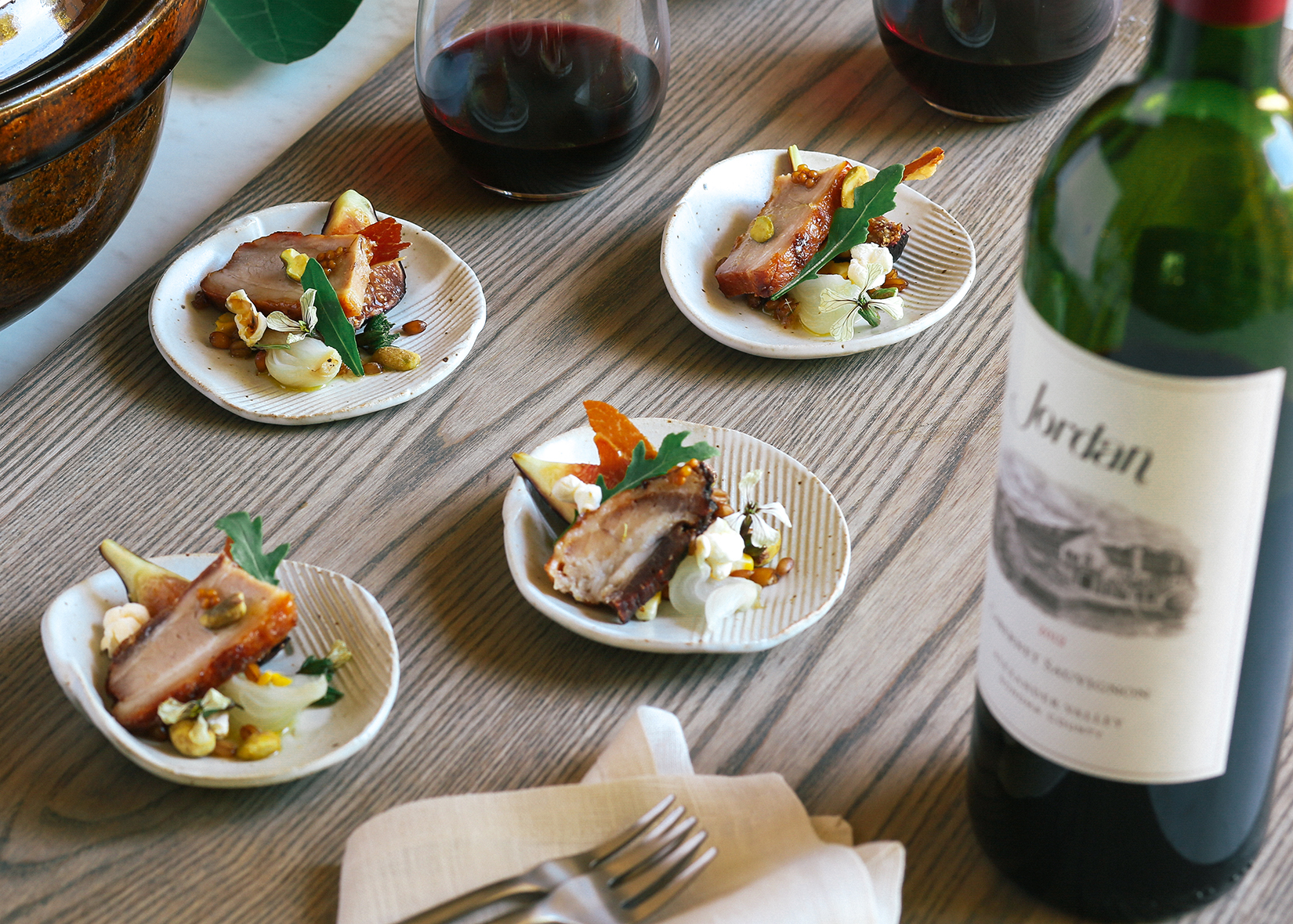 Heritage Pork Belly with Smoked Fig next to a bottle of Jordan wine