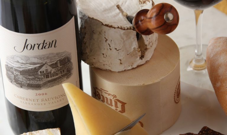 a bottle of Jordan Winery 2006 Cabernet next to a wheel of cheese