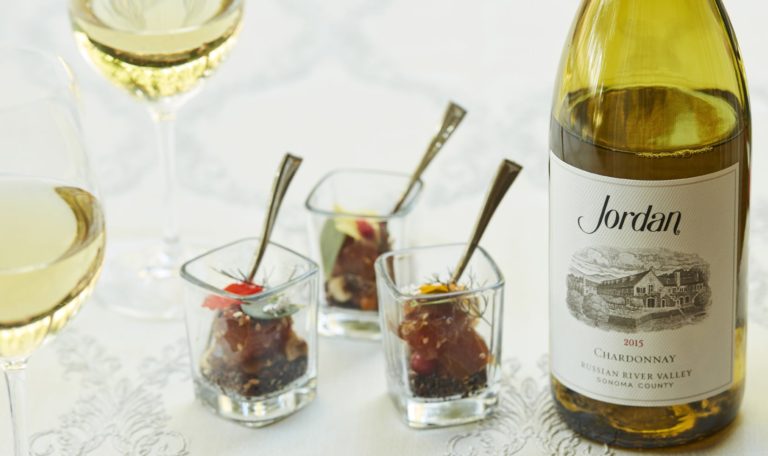 Jordan Winery 2015 Chardonnay next to appetizer food bite and poured glasses