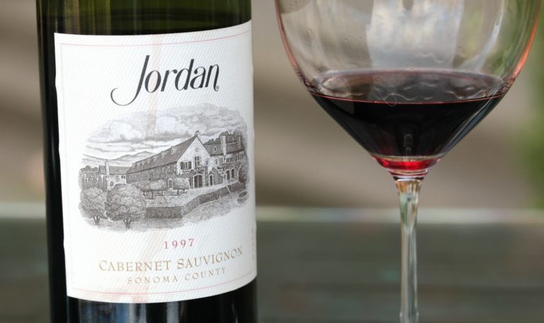 a bottle of 1997 Jordan Winery Cabernet Sauvignon beside a poured taste in a glass