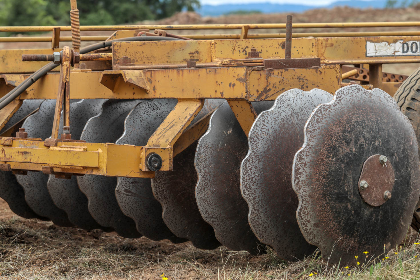 Close-up of soil deep ripping tractor's row of gear shaped blades.
