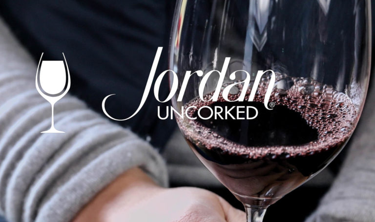 still from a video made by Jordan Winery featuring a close up of a hand holding a glass of Jordan Winery Cabernet with image text: "Jordan Uncorked"