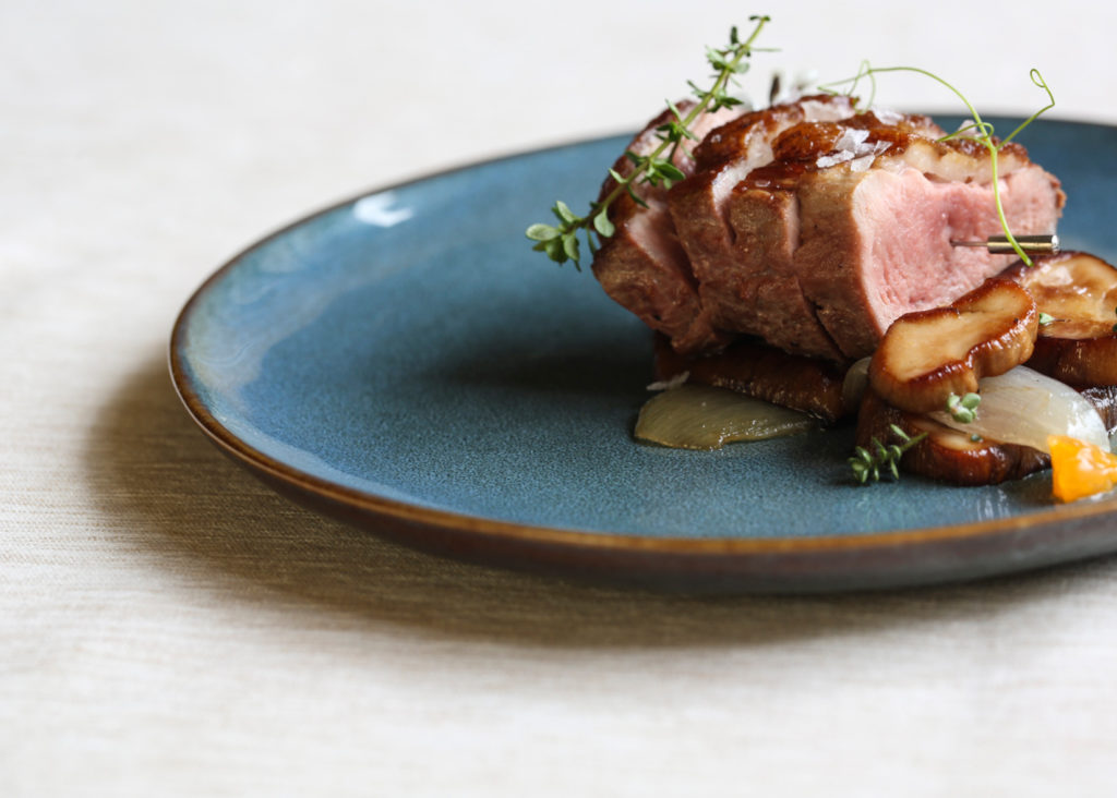 Roasted Duck Breast and Porcini Mushrooms on a blue plate