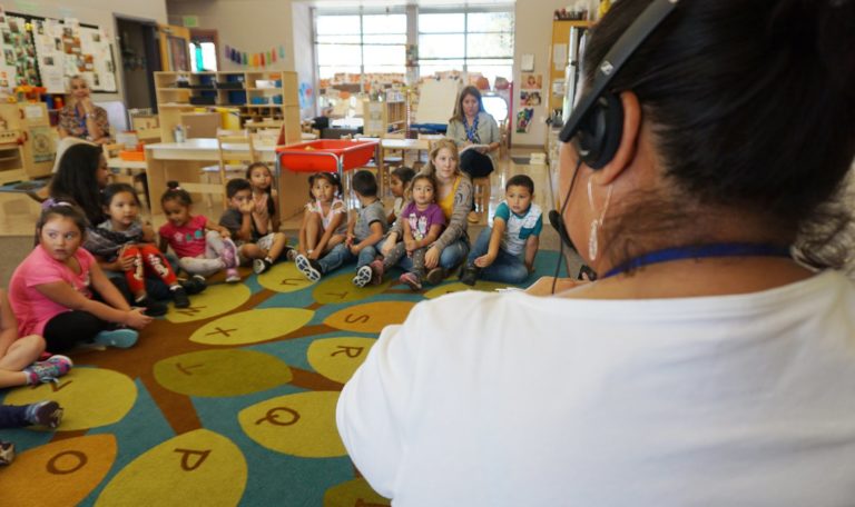 a preschool teacher addressing a class of students using her TALLK headset donated by the John Jordan Foundation