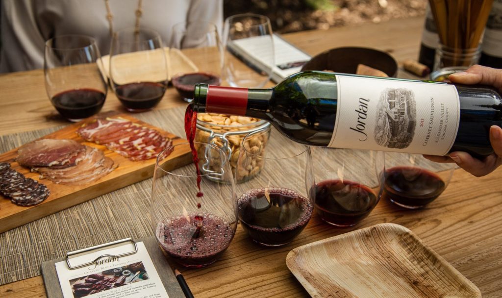 hand pouring Jordan Winery Cabernet in wine glass with journeyman charcuterie during a Chateau Block tasting experience at Jordan Winery