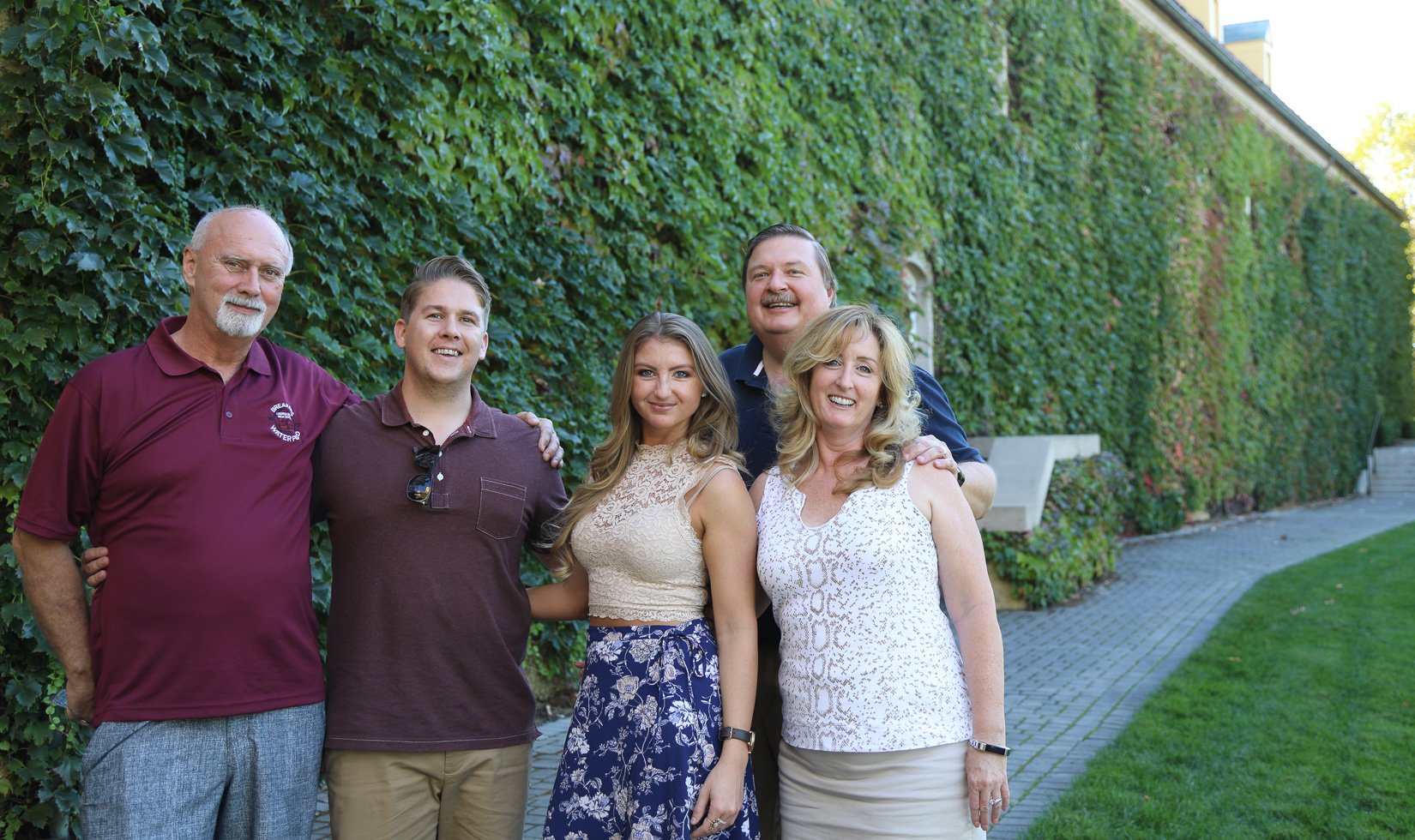 5 guests at Jordan Winery in wine country casual attire. The three men have polo shirts and the women wear floral lace tops.