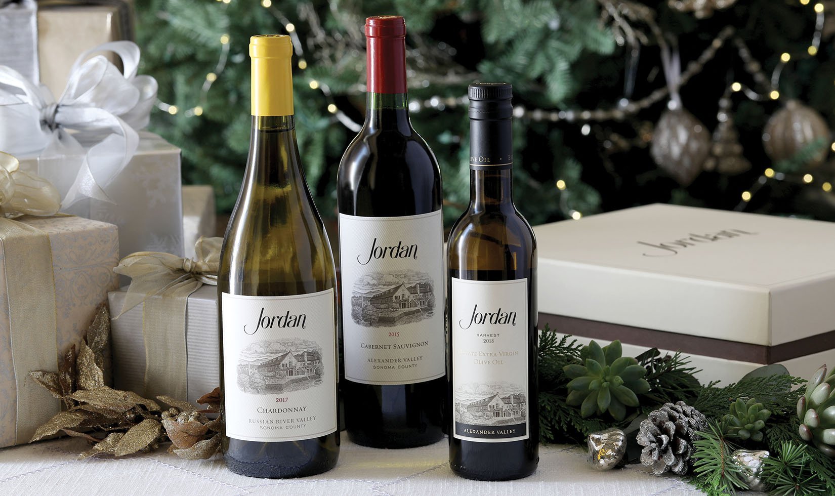 2017 Jordan Chardonnay, 2015 Jordan Cabernet Sauvignon and 2017 Olive Oil with three bottle gift box in front of Christmas tree