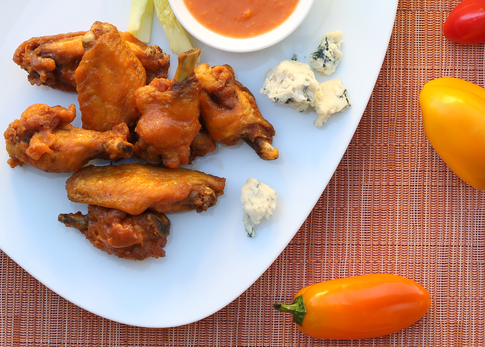 Citrus Spiced Fried Chicken Wings on white plate next to peppers