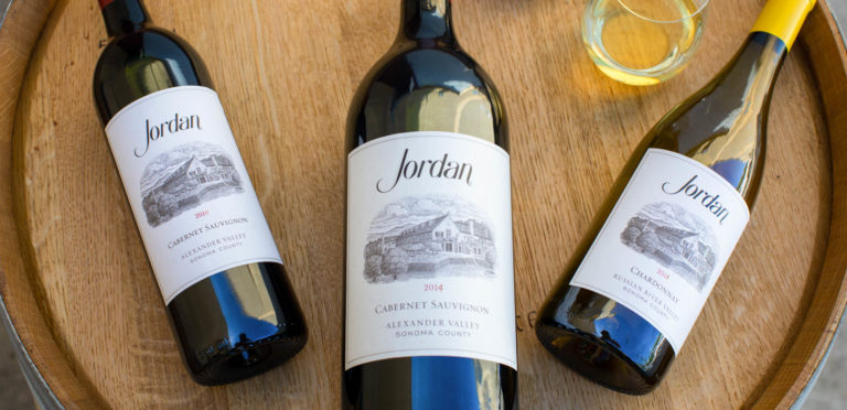 jordan chardonnay and cabernet sauvignon wine bottles on wine barrel