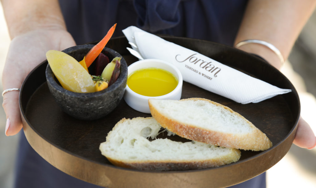 tray with sliced bread, white dish of olive oil and cured vegetables