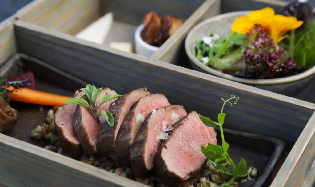 sliced lamb on bed of farro and salad greens