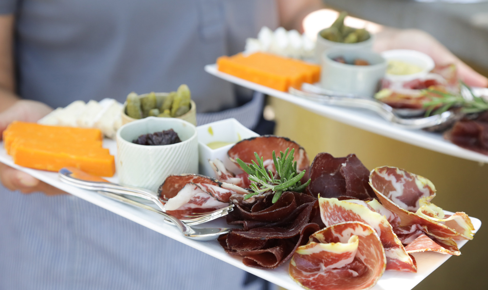 Person carrying plates of charcuterie food