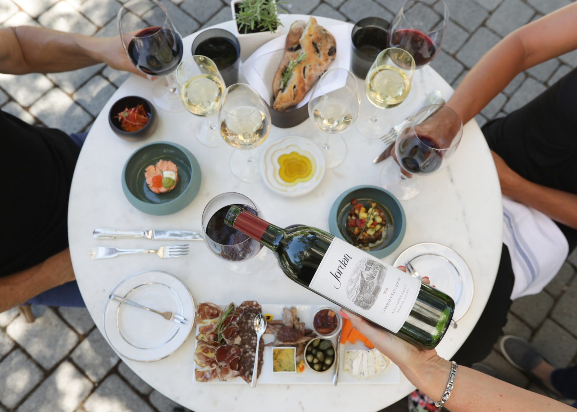 Hand pouring Jordan Cabernet Sauvignon at an outside table set with food