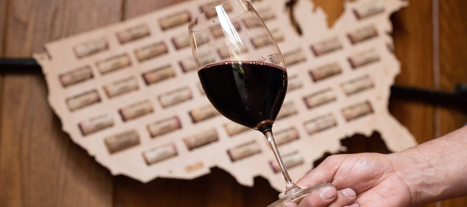 hand holding cabernet wine glass in front of map of united states