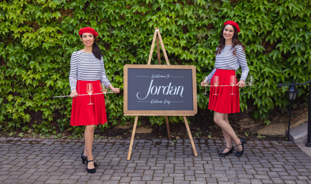 two women in French-themed costumes in front of green ivy wall