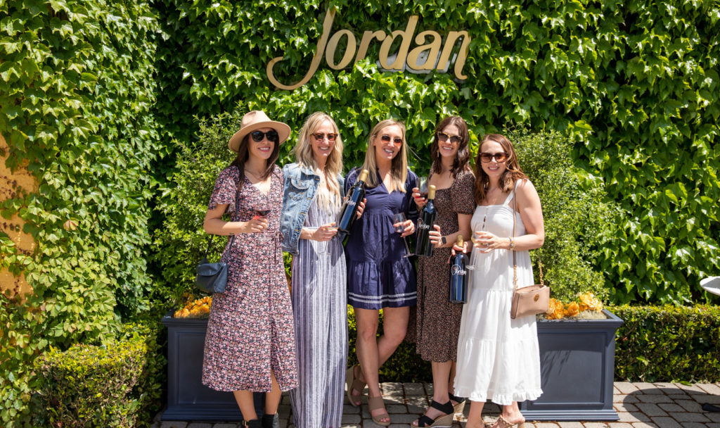 group of women standing in front of green ivy wall