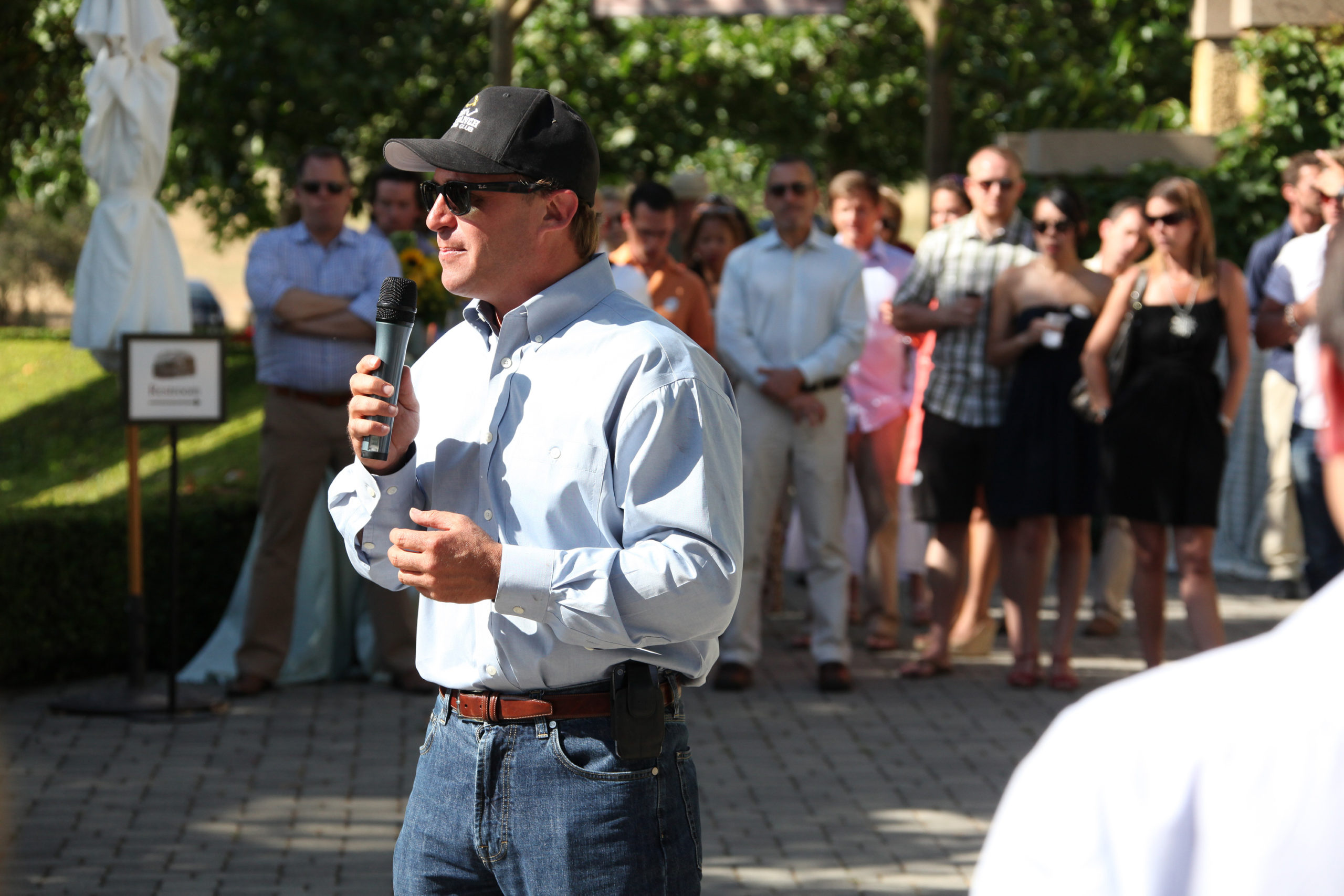 Person speaking with microphone. Other people in background