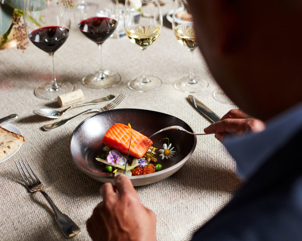 Person enjoying salmon dish with Jordan Cabernet Sauvignon and Jordan Chardonnay