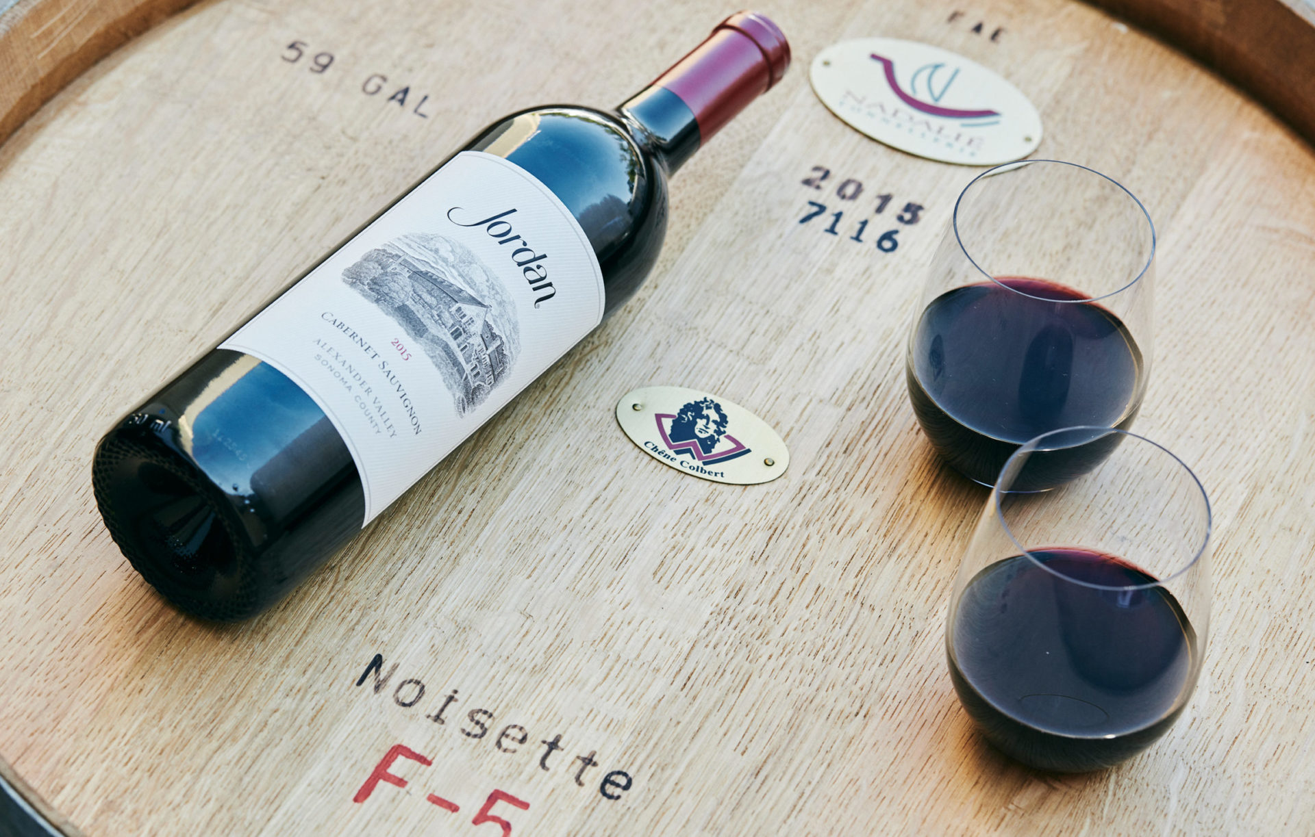 Bottle and glasses of Jordan Cabernet Sauvignon on a barrel
