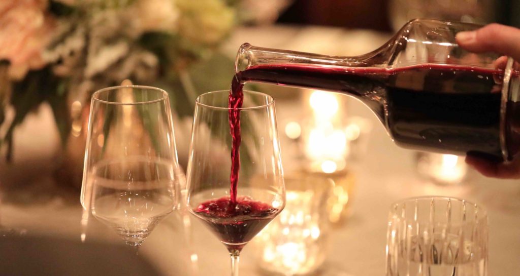 decanter of cabernet wine pouring at candlelit table
