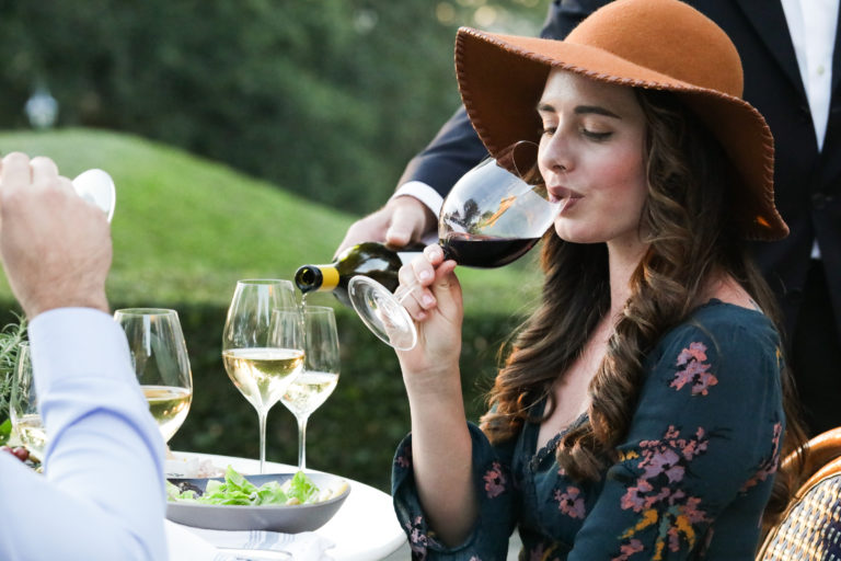 woman sitting at table sipping a glass of cabernet wine