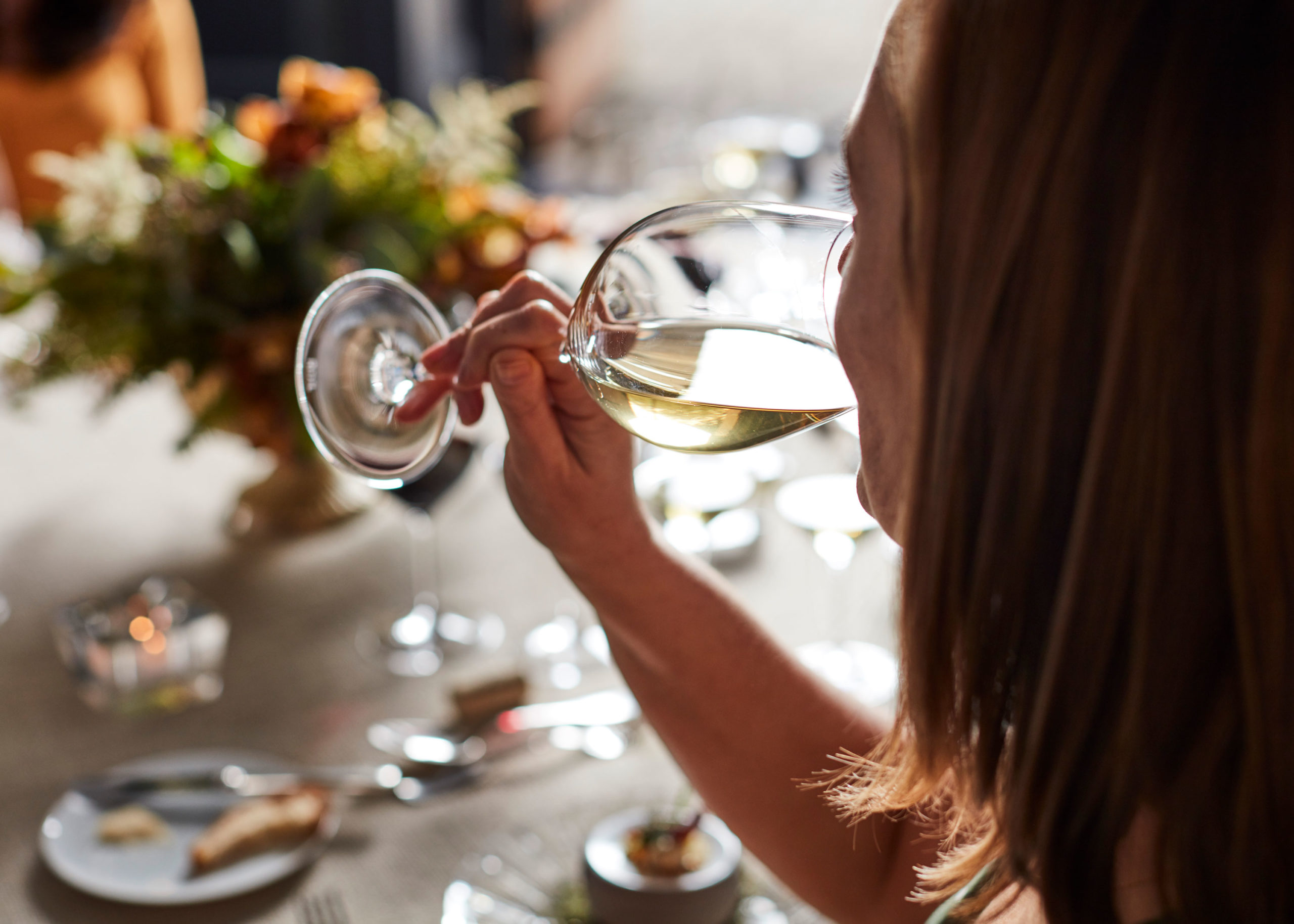 Person drinking Jordan Chardonnay with table setting in background