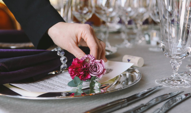 Person placing flowers at a place setting