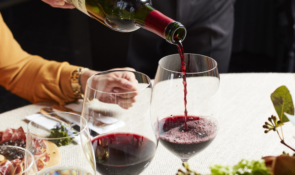 Hand pouring Jordan Cabernet Sauvignon for a person at a table