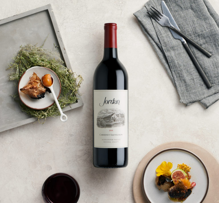 Jordan Cabernet Sauvignon on tabletop with place setting and food