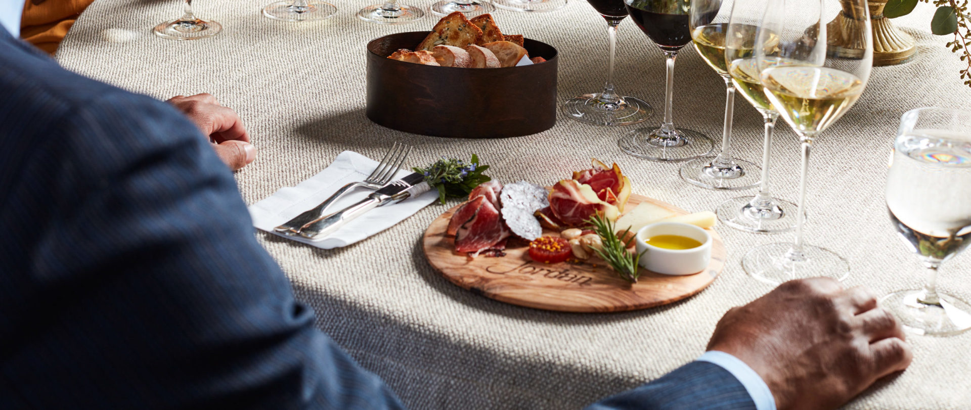 Person enjoying artisanal salumi and cheeses paired Jordan Cabernet Sauvignon and Jordan Chardonnay at a table