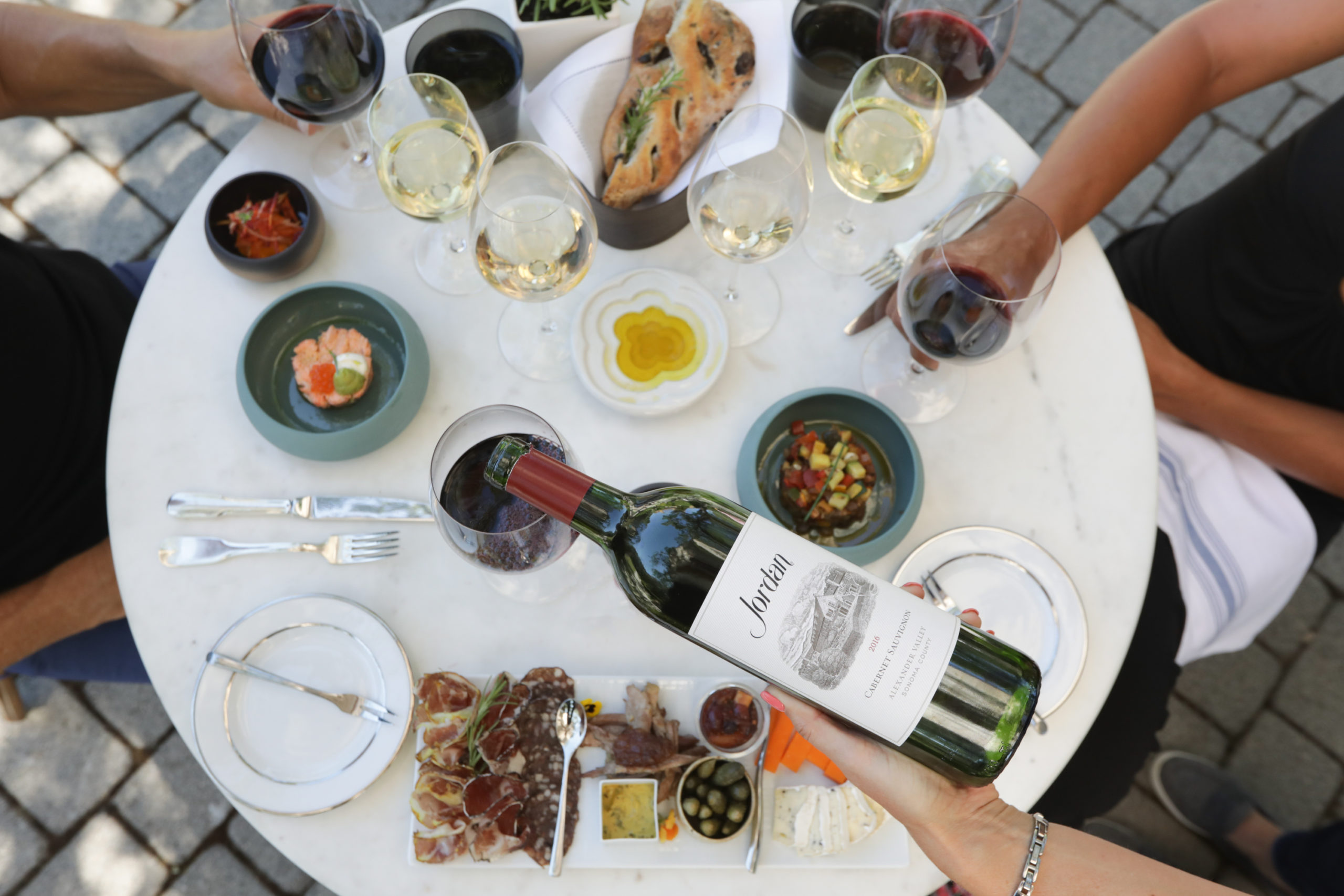 People around a table set with Jordan Cabernet Sauvignon, Jordan Chardonnay and food