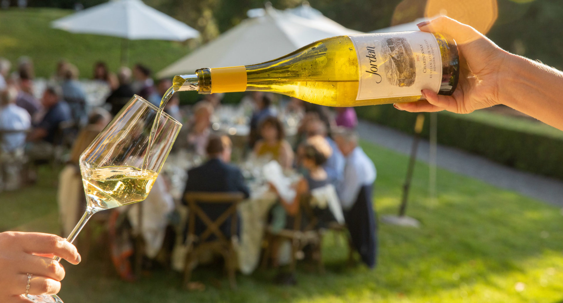 Pouring Jordan Chardonnay outside with tables full of people behind