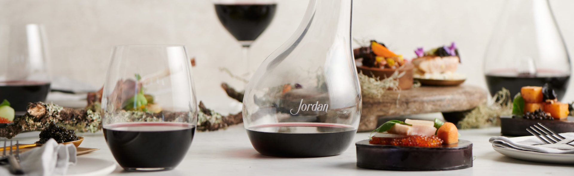 Decanter and glasses of Jordan Cabernet Sauvignon with food and branches