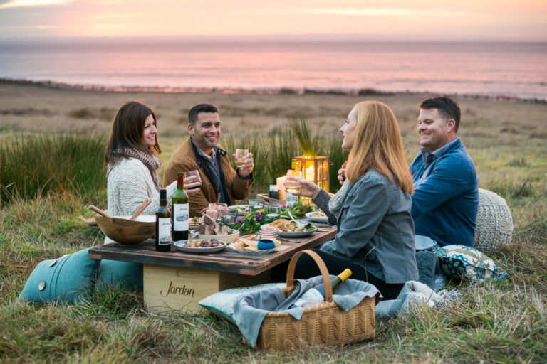 People enjoying Jordan wine during a picnic at the ocean