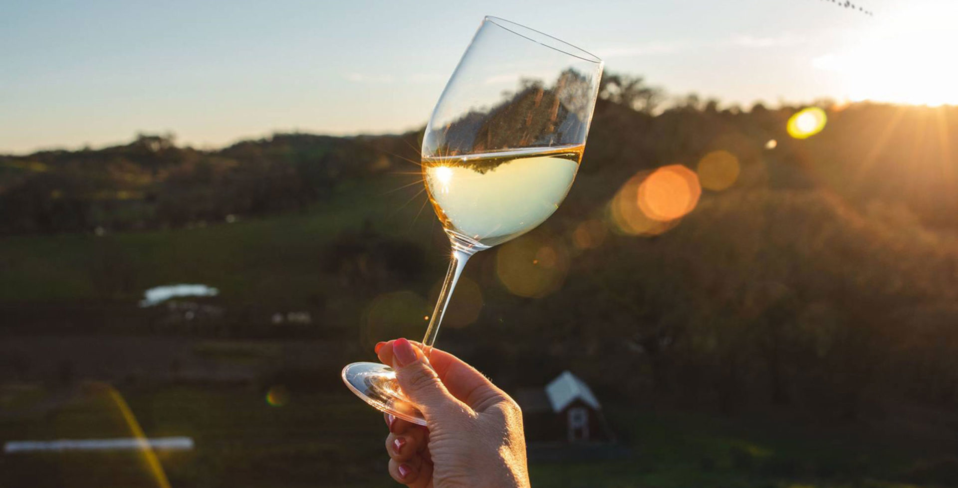 A sunset showing behind a glass of Jordan Chardonnay