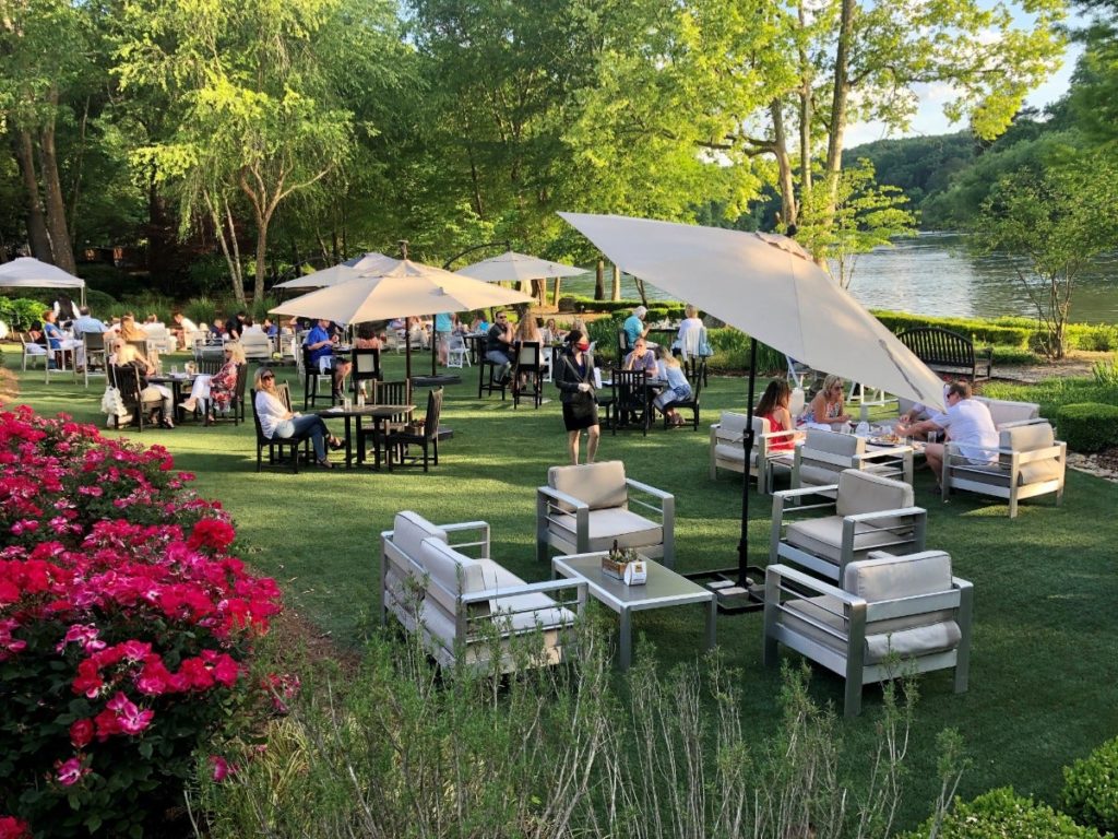 Guests sitting at tables on a lawn by a river
