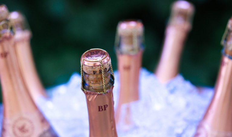 Close-up of the top of a pink Bruno Paillard rosé bottle. It sits in an ice bucket surrounded by 5 more bottles.