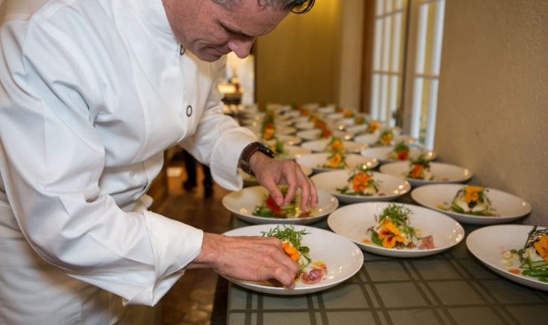 A chef puts the final touches on the last floral appetizer in a long row of servings.